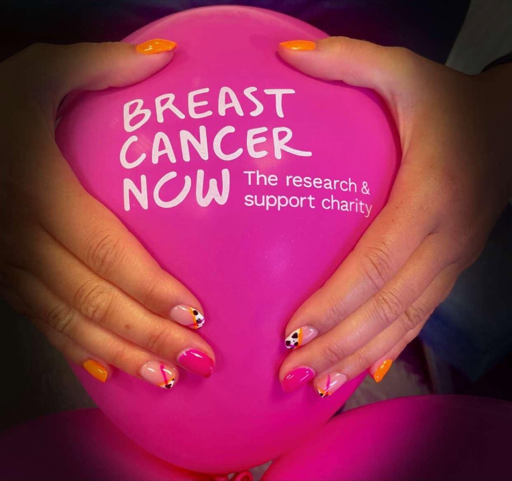 Hands with pink ribbon nail designs holding a pink Breast Cancer Now balloon